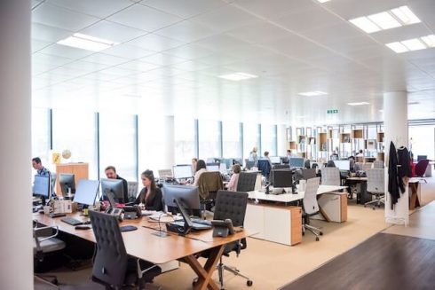 Imagen de una bulliciosa oficina con numerosos escritorios y trabajadores ocupados en sus tareas.